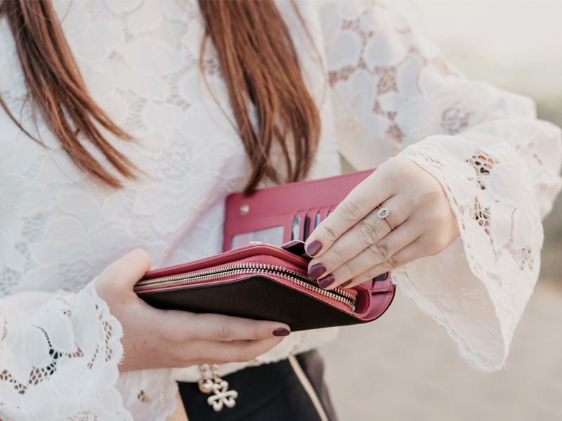 レザーの長財布からカードを取ろうとしている若い女性